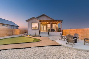 A house with a covered patio, a small lawn, and a seating area. - Arch Ray  Retreat - Luxury Home w/firepit & grill (Fredericksburg)