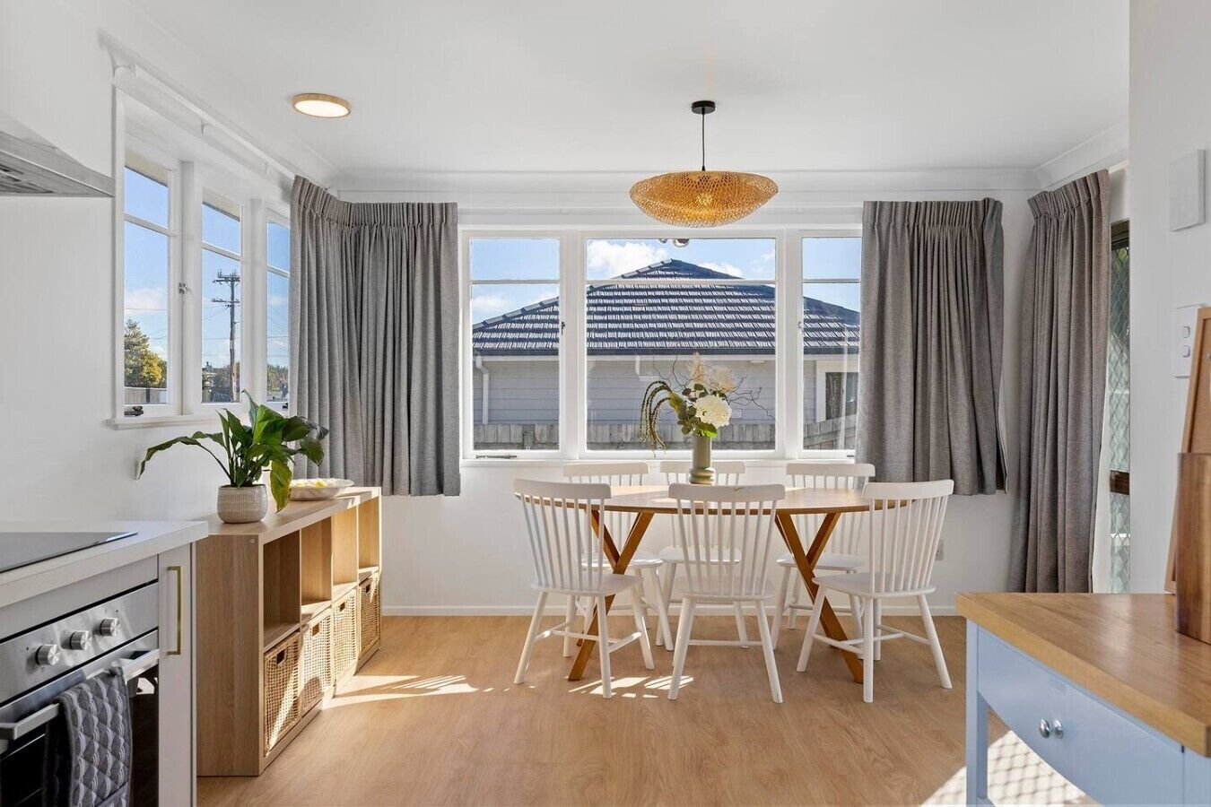 A modern kitchen with white cabinetry, a dining area with a round table and white chairs, and a large window with a view of a mountain.
