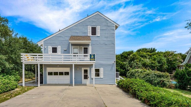 A two-story house with a garage, a balcony, and a well-maintained lawn. - Litts Go Play-Soundside retreat with 4 bedrooms, deck, and ocean views. (Kitty Hawk)