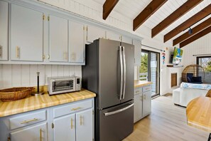 A modern kitchen with white cabinetry, a stainless steel refrigerator, a built-in microwave, and a wooden countertop. - Litts Go Play-Soundside retreat with 4 bedrooms, deck, and ocean views. (Kitty Hawk)