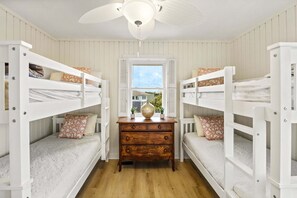 Ein Zimmer mit Etagenbetten, einem Holzschrank und einem Fenster mit Rollläden.