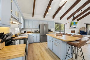 Une cuisine moderne avec des meubles de couleur bleu clair, des appareils en acier inoxydable et un îlot central en bois.
