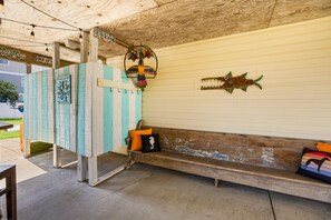 A rustic outdoor seating area with a wooden bench and a wall-mounted fish decoration. - Till Next Time - hot tub, tiki bar, EV charger, and beach access. (Kill Devil Hills)