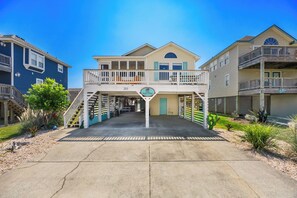 A two-story building with a balcony, a sign reading 'Till Next Time', and a number '203' on the front. - Till Next Time - hot tub, tiki bar, EV charger, and beach access. (Kill Devil Hills)