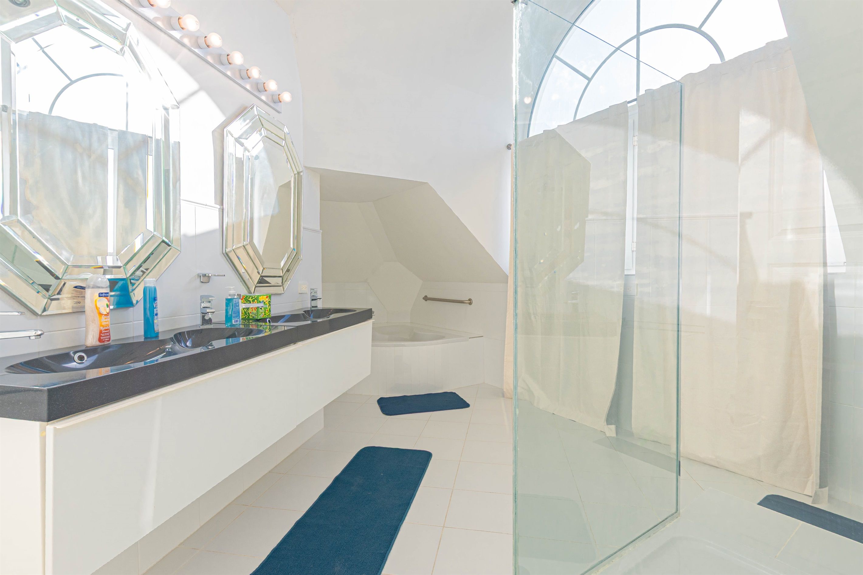 A modern bathroom with a large mirror, a bathtub, and a glass shower enclosure.