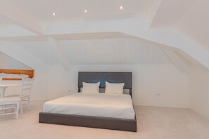 A bedroom with a bed, a desk, and a chair. - Love Beach W4 - Penthouse Steps to Pool & Beach (Nassau)