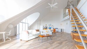 Un loft spacieux avec un plafond haut, un escalier en bois et un coin cuisine moderne.