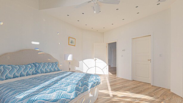 Een slaapkamer met een bed, een plafondventilator, inbouwverlichting, een deur en een gang.