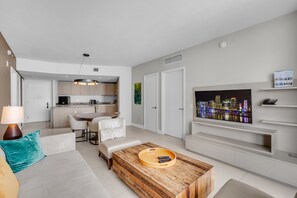 A modern living room with a flat-screen TV, a wooden coffee table, and a sofa. - LYFE Resort | 24th Floor Ocean View + Balcony (Hollywood)