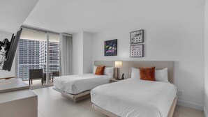 A hotel room with two beds, a desk, and a view of a cityscape. - Oceanview Highrise - Amenities- 6 people (Hollywood)