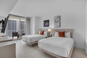 A hotel room with two beds, a desk, and a view of a cityscape. - Oceanview Highrise - Amenities- 6 people (Hollywood)