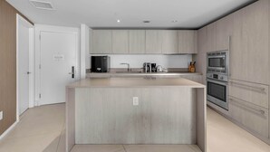 A modern kitchen with a central island, built-in appliances, and a minimalist design. - Oceanview Highrise - Amenities- 6 people (Hollywood)