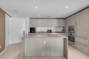 A modern kitchen with a central island, built-in appliances, and a minimalist design. - Oceanview Highrise - Amenities- 6 people (Hollywood)