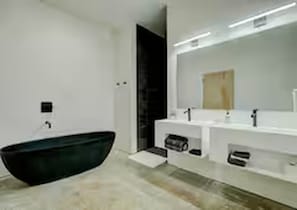 Ein modernes Badezimmer mit freistehender Badewanne, einem großen Spiegel und einem weißen Waschtisch.