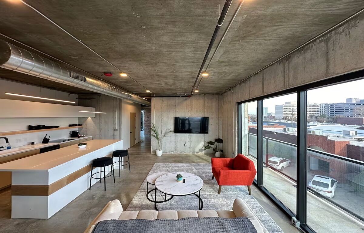 A modern interior with a kitchen, dining area, and seating space with a city view.