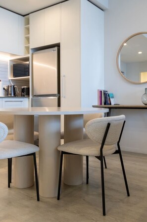 A modern kitchen with white cabinetry, a stainless steel refrigerator, and a round mirror on the wall. - Heart of CBD - Walk to ONE NZ Stadium + Parking (Christchurch)