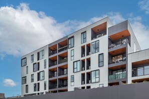 A multi-story building with balconies, large windows, and a flat roof. - Heart of CBD - Walk to ONE NZ Stadium + Parking (Christchurch)