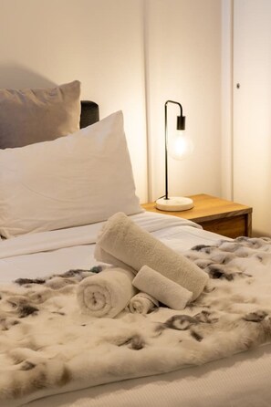 Ein Bett mit einer flauschigen Decke, einer Nachttischlampe und einem Holznachttisch.