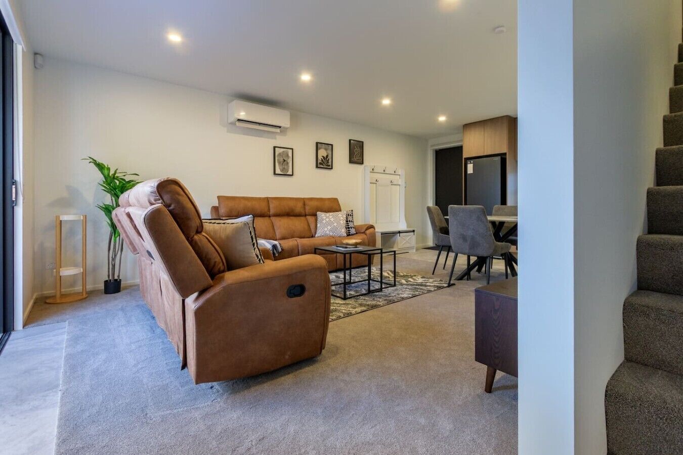 A modern living room with a sofa, coffee table, and a dining area with chairs.