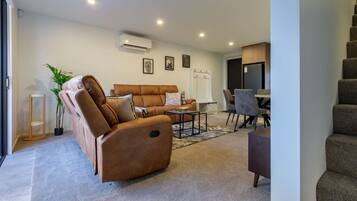A modern living room with a sofa, coffee table, and a dining area with chairs.