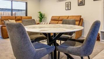 A modern living room with a round table and four chairs, a sofa, and a potted plant.