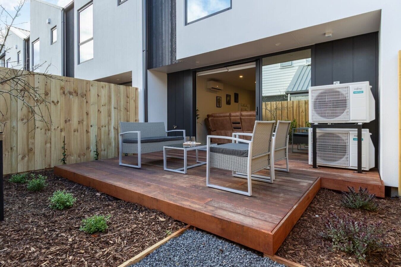 A modern outdoor patio with a sofa, chairs, and a table.