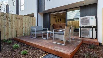 A modern outdoor patio with a sofa, chairs, and a table.