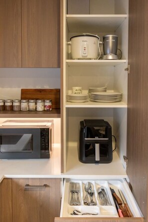 A kitchen with a microwave, a coffee maker, and a drawer with utensils. - Ultimate City Comfort - Carpark + EV (Christchurch)