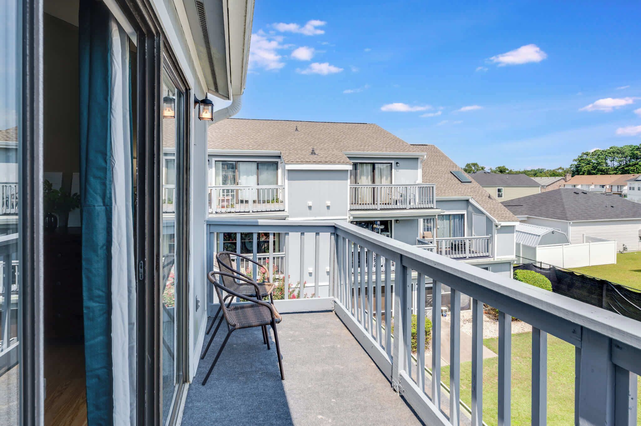 A balcony with a chair, a railing, and a view of neighboring houses.