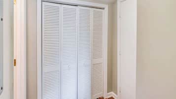 A closed white closet with horizontal louvered doors and a white door to the right.