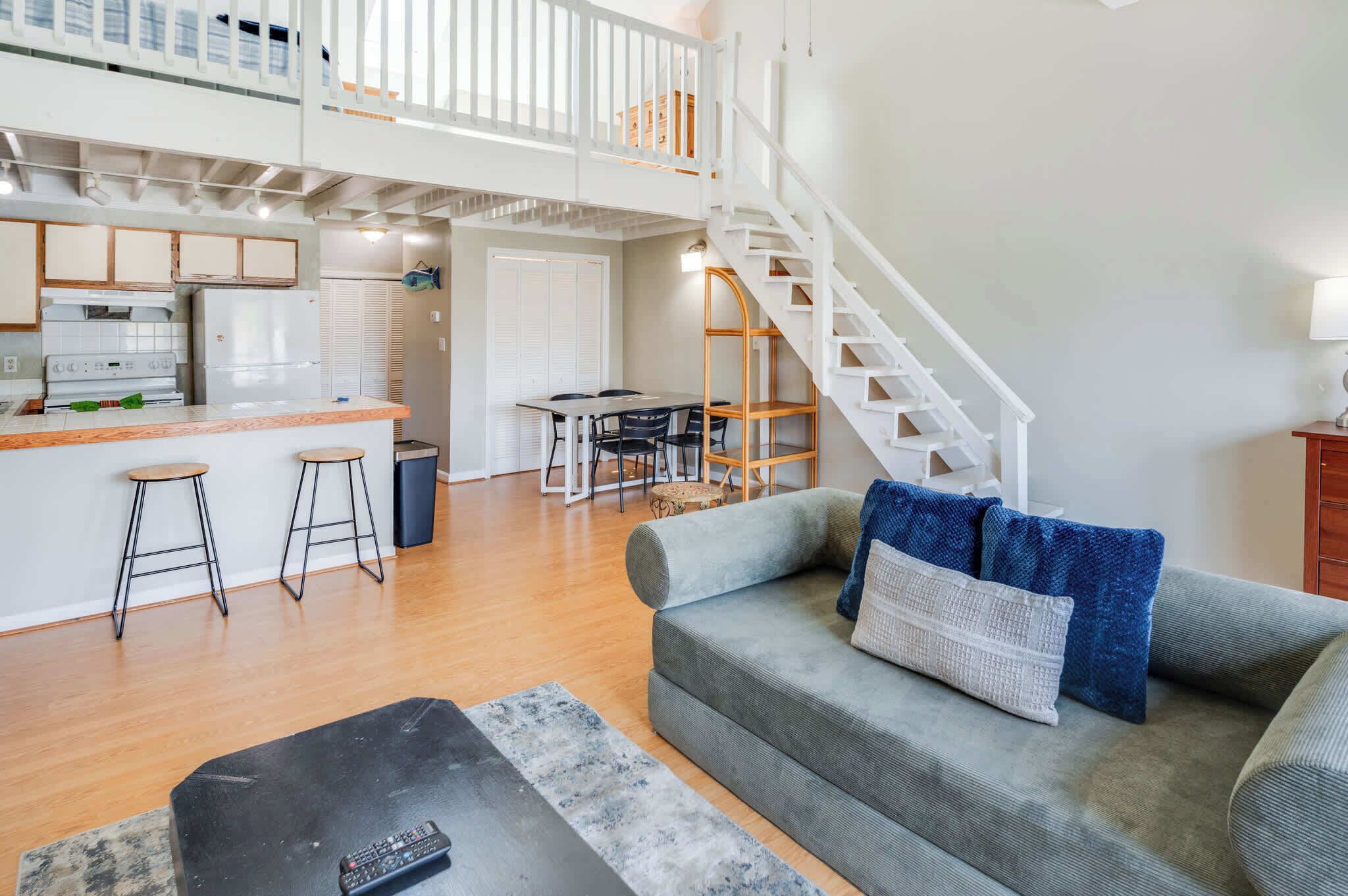 A spacious living area with a kitchen, dining table, and a staircase leading to an upper level.
