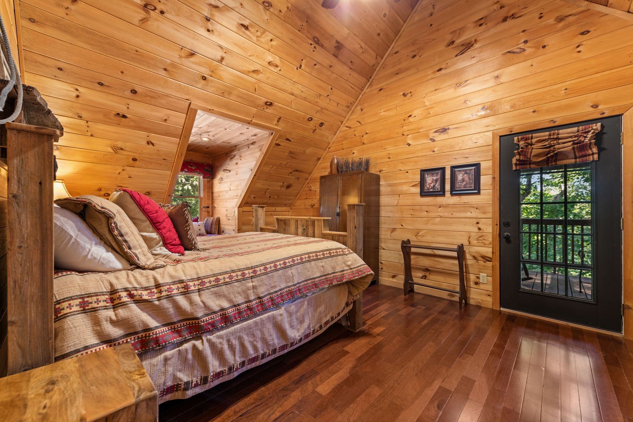 Un dormitorio tipo cabaña de madera con cama, ventana y puerta.