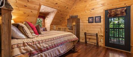 Un dormitorio tipo cabaña de madera con cama, ventana y puerta.