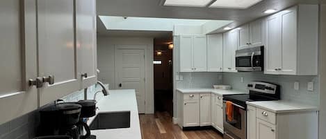 A modern kitchen with white cabinets, a microwave, an oven, and a coffee maker.