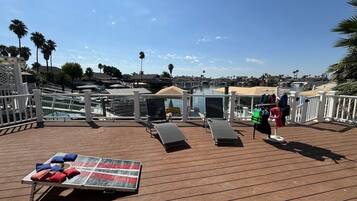 A sun deck with lounge chairs, a table with cushions, and a clothing rack.