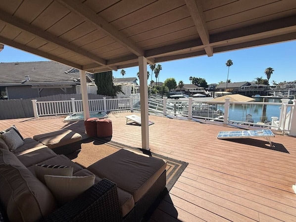 A covered outdoor deck with a pool, lounge chairs, and a seating area.