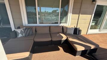 Ein Ecksofa mit Chaiselongue, ein Korbtisch und eine Schiebeglastür.