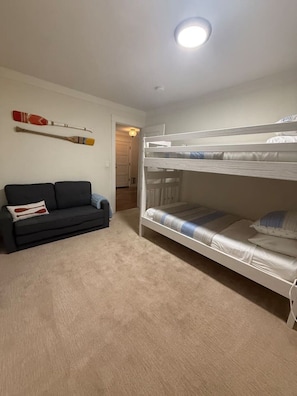 A room with a bunk bed, a sofa, and a wall-mounted paddleboard. - 5 mins to fast water with hot tub and boat rental (Discovery Bay)