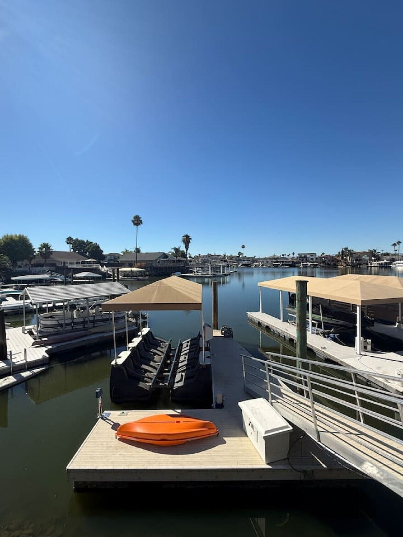 Un port de plaisance avec des bateaux amarrés, une bouée de sauvetage sur le quai et un ciel bleu dégagé.