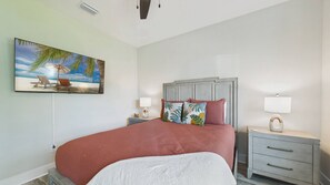 Une chambre à coucher comprenant un lit, une table de chevet, une lampe, un tableau accroché au mur et une bouche d’aération au plafond.