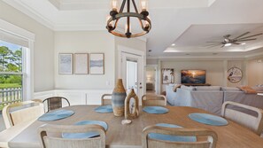 Un coin repas avec une table ronde, des chaises et un lustre. On y trouve également un téléviseur et des œuvres d’art accrochées au mur.