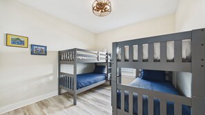 A room with bunk beds, a ceiling fan, and two framed pictures on the wall. - Blue Heron Laguna Haven 253-West End-Sleeps 12 (Panama City Beach)