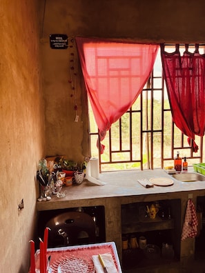 A kitchen with a window, a sink, and various kitchen utensils.