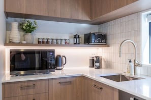 A modern kitchen with a microwave, coffee maker, and a coffee grinder on the countertop. - Peaceful Family CBD Stay w/ Car Park + EV charger (Christchurch)
