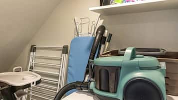 A laundry room with a washing machine, a dryer, and a vacuum cleaner.