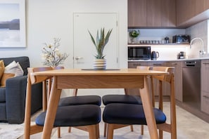 A modern kitchen with wooden cabinets, a built-in oven, and a coffee machine. - Peaceful Family CBD Stay w/ Car Park + EV charger (Christchurch)