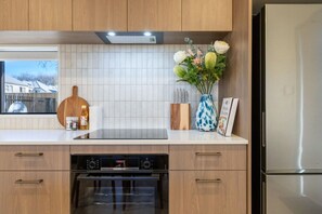 Eine moderne Küche mit Holzschränken, einem eingebauten Backofen und einem Edelstahl-Kühlschrank.