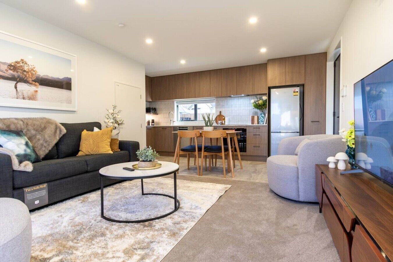 Uma sala de estar moderna com sofá, mesa de centro e área de jantar com cadeiras.