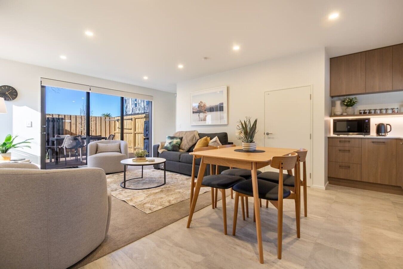 A modern living room with a sofa, a dining table, and a kitchen area with cabinets and appliances.