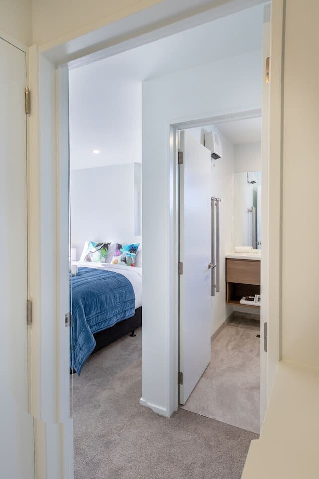 A hotel room with a bed, a bathroom, and a hallway.